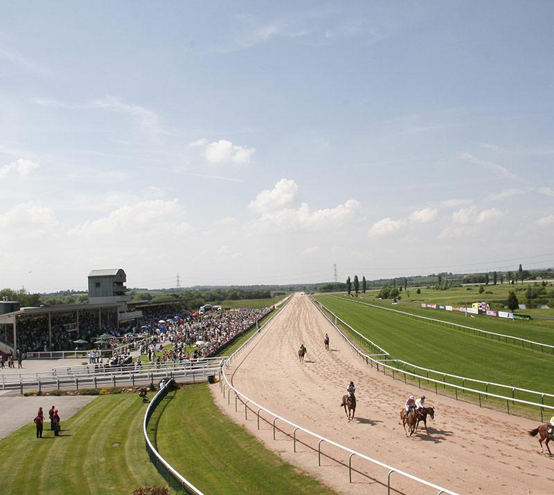 Raceday at Southwell Racecourse, with crowds watching the action from the grandstand.