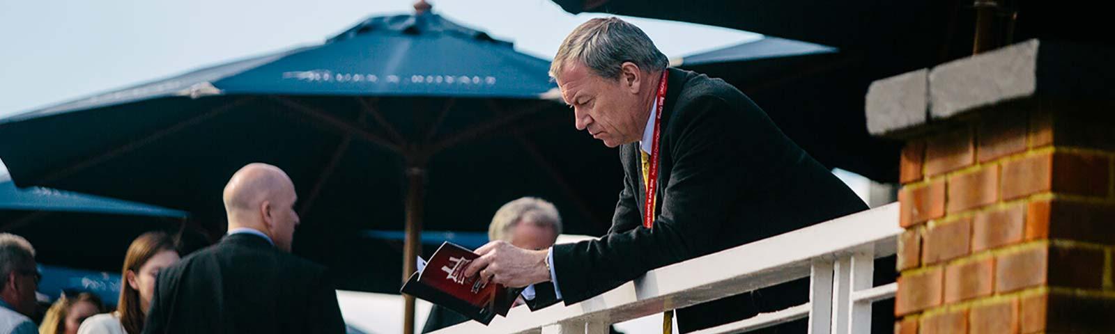 A man reading through a All Weather Championships guide.